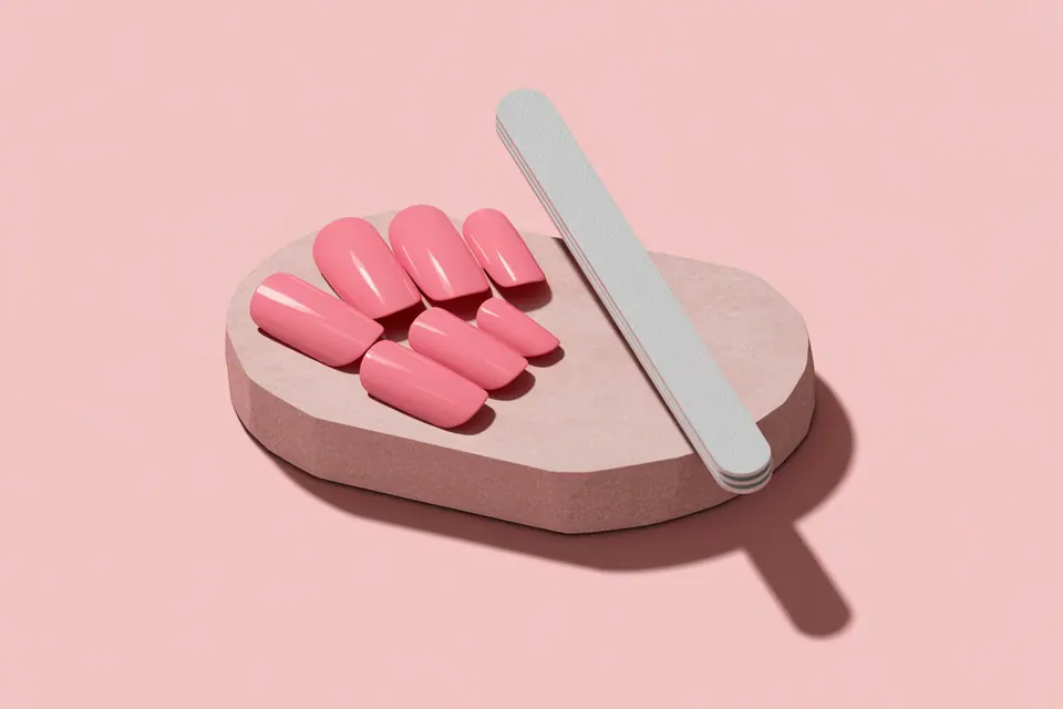 Pink manicure sample tips and a nail file arranged on a stone display.